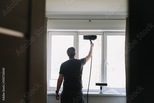 Man washing and cleaning window at home. Housework and housekeeping, home hygiene
