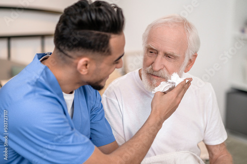 Caretaker getting an elderly man ready for a shave