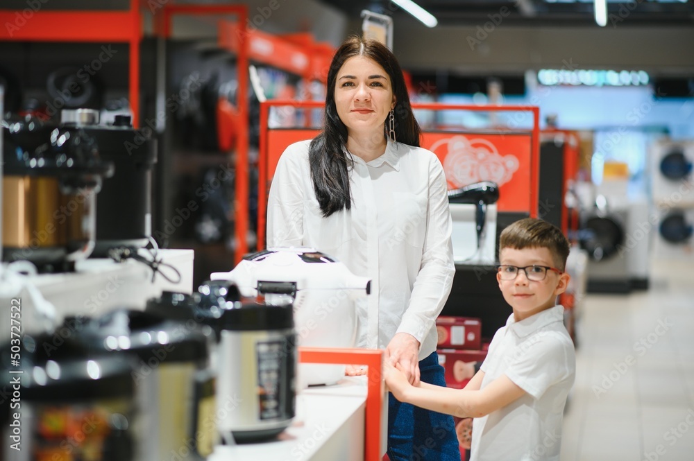 Obraz premium Happy mother with son in home appliance store.