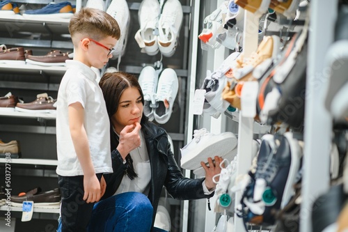 Mother with children choosing shoes in kids store