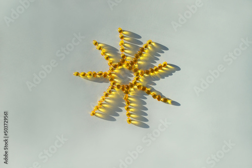 Sun from vitamin d capsules. Sunshine vitamin. Capsules are laid out in the shape of the sun on a blue background