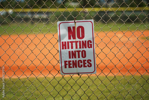 No hitting into fences sign on baseball field.