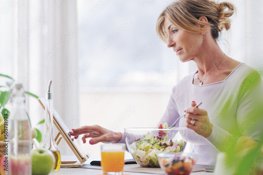 Woman having lunch and connecting with her tablet Woman having lunch and connecting with her tablet