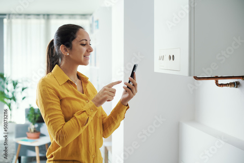 Woman managing her smart boiler using her phone photo