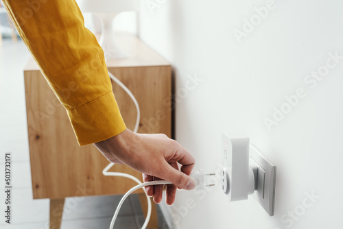 Fotografie Woman plugging a device into a smart plug