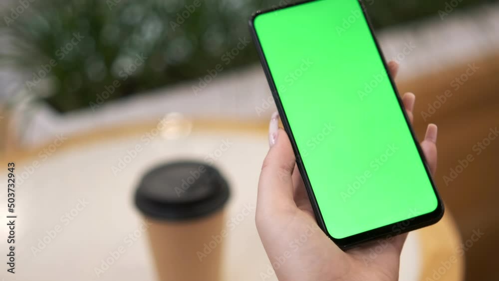 Business woman sitting in the food area of the mall using smartphone viewing green screen on mobile phone browsing chroma key online watching enjoying drinking coffee reading social media close up