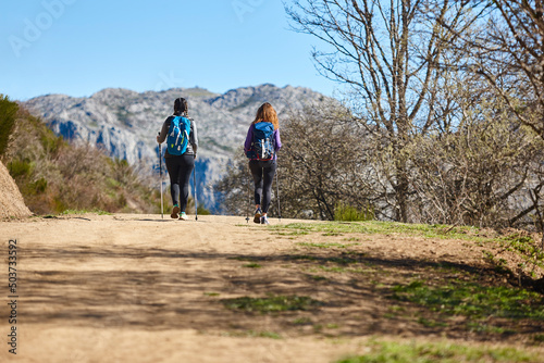 Two female backpacker hikers on a pathway. Mountain trekking