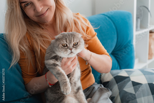 Fotografie Portrait of a cute domestic purebred cat lying with the owner of the house