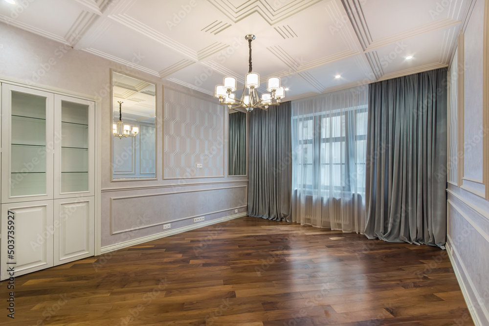 Fototapeta premium A spacious living room without furniture with original decorated walls and ceiling. Brown parquet.