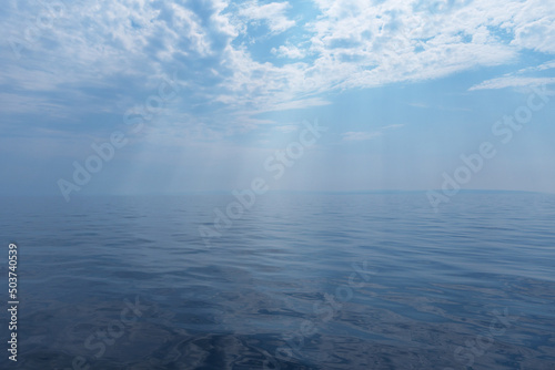 Calm sea and cloudy sky pierced with sun rays. Beautiful nature background.