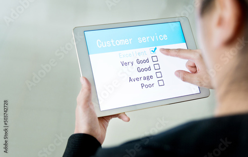 Close-up of woman filling online customer service satisfaction survey on digital tablet