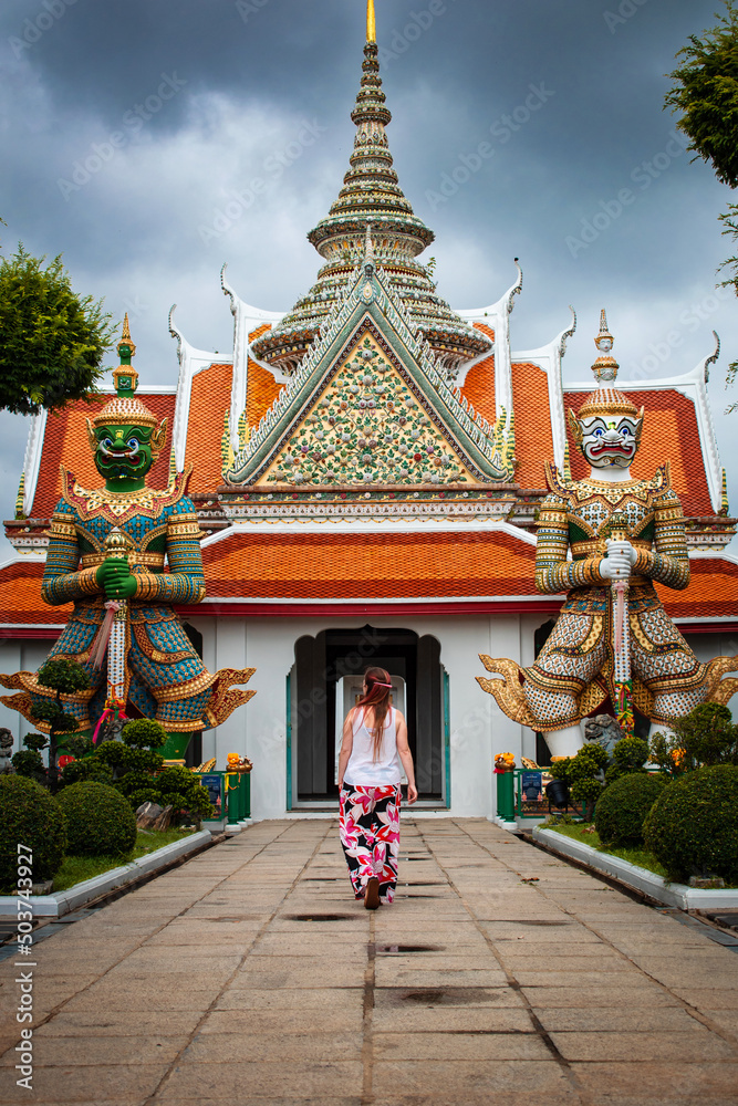 Mujer turista entrando a las puertas de templo budista, Wat Pho, en Bangkok, Tailandia