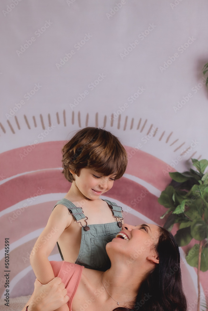 Naklejka premium Mother and son hugging and playing for mothers day with flowers 