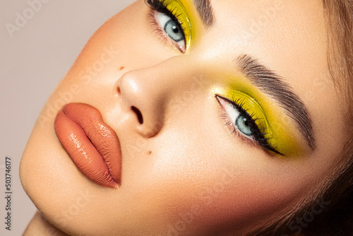 Photo Face of a blue-eyed female model with vibrant make-up and a hoot look