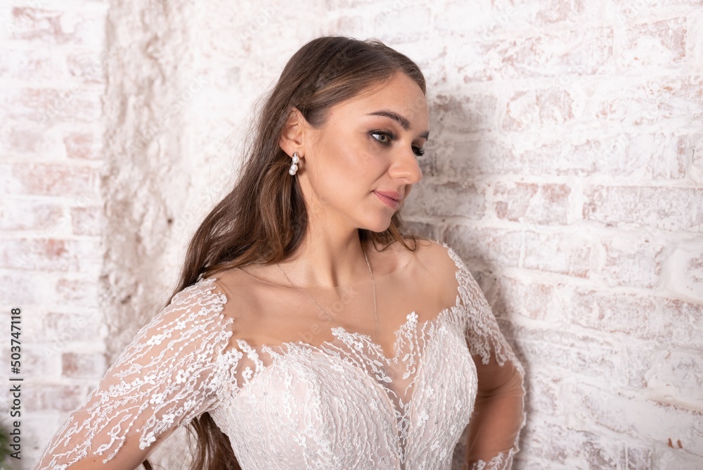 Fototapeta premium Close-up portrait of a bride against a white brick wall.