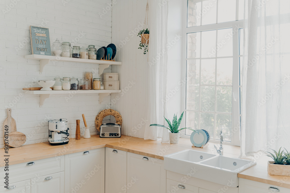 Fototapeta premium Brightly lit scandinavian kitchen with large window. Concept of mortgage and modern apartment.