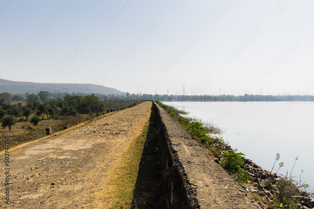 Panoramic landscape view of a rocky walkway on the perimeter wall of Kurje Dam also known as Dapchari Dam located in Palghar district, Maharashtra, India