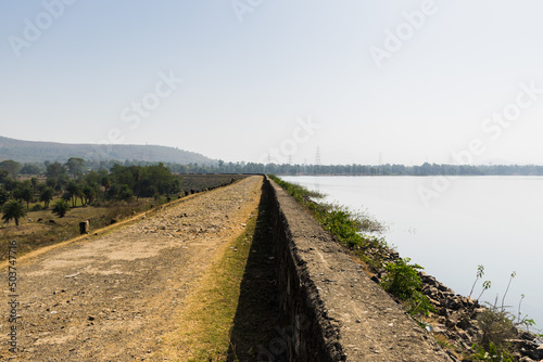 Fototapeta Naklejka Na Ścianę i Meble -  Panoramic landscape view of a rocky walkway on the perimeter wall of Kurje Dam also known as Dapchari Dam located in Palghar district, Maharashtra, India