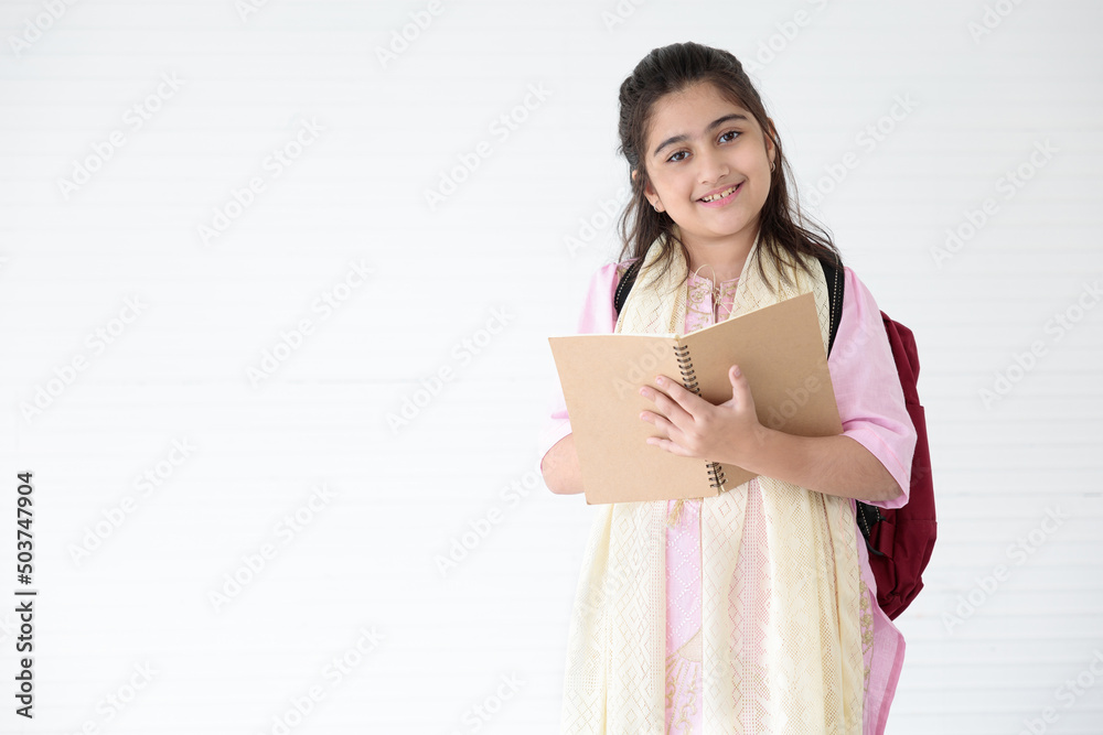 cute Indian girl smiling and writing on notebook for learning, education concept cute Indian girl smiling and writing on notebook for learning, education concept