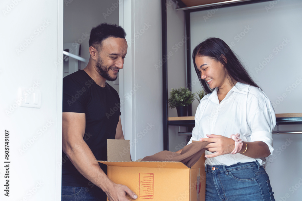 An Asian and Caucasian couple are packing boxes to move house, where they live happily using tape to seal the boxes in preparation for moving. An Asian and Caucasian couple are packing boxes to move house, where they live happily using tape to seal the boxes in preparation for moving.