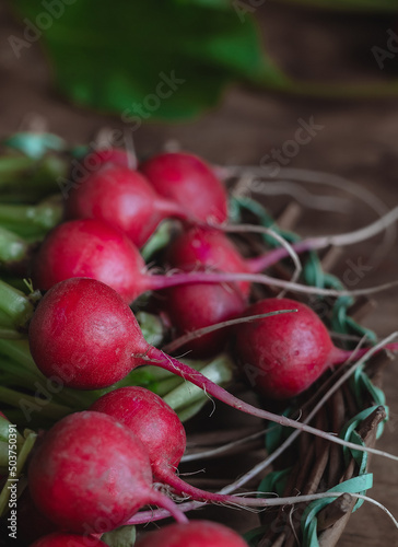 Fresh red radish in a basket on a dark wooden background.