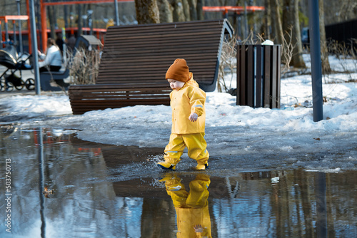 a child walks through puddles in the park
