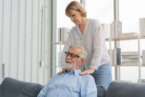 Health  body muscles stiff problem of senior couple  caucasians mature  adult retired husband  wife pain with back pain ache holding massaging rubbing shoulder hurt or sore  painful sitting on sofa.