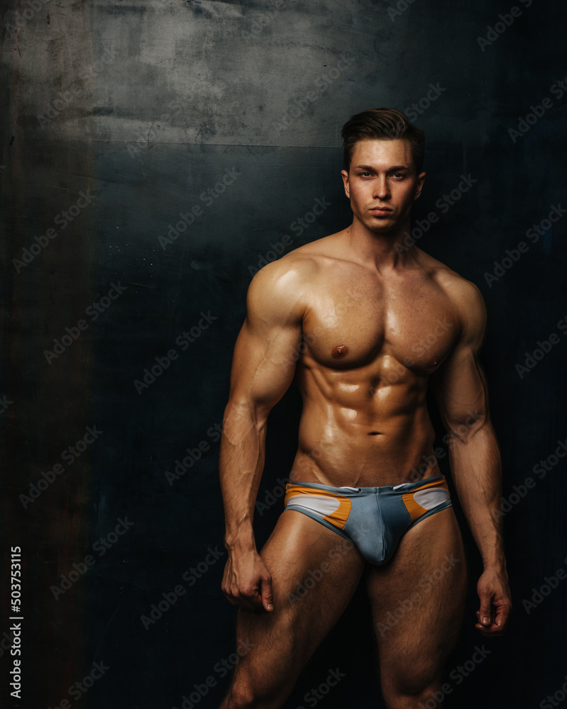 Handsome fitness male model in swimwear posing in studio