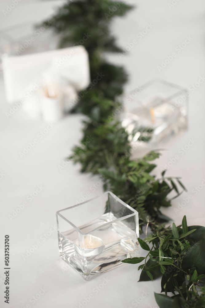 Decor of candles and green flowers on the wedding table in the restaurant. Decor of candles and green flowers on the wedding table in the restaurant.