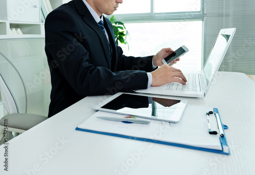 Businessman in office using laptop, tablet and smart phone on the desk