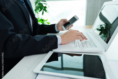 Businessman in office using laptop, tablet and smart phone on the desk