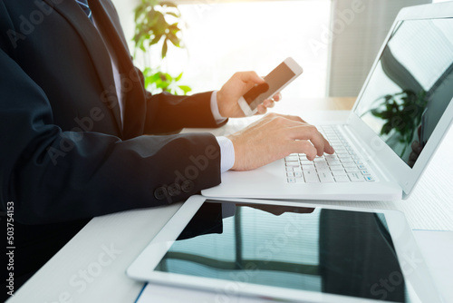 Businessman in office using laptop, tablet and smart phone on the desk
