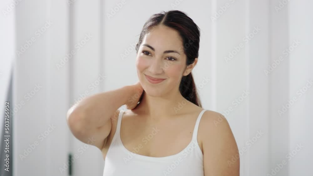 Beautiful hispanic woman caresses shoulder, neck admiring herself in the mirror Beautiful hispanic woman caresses shoulder, neck admiring herself in the mirror
