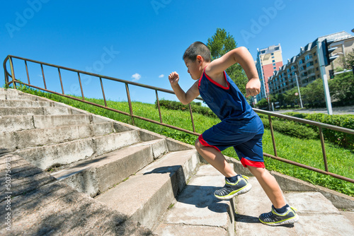 Rear view of young boy running up on steps © xy