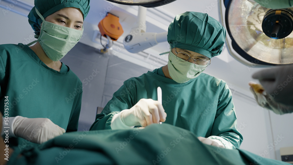 Asian doctor uses a scalpel to the patient with surgical team in operating room