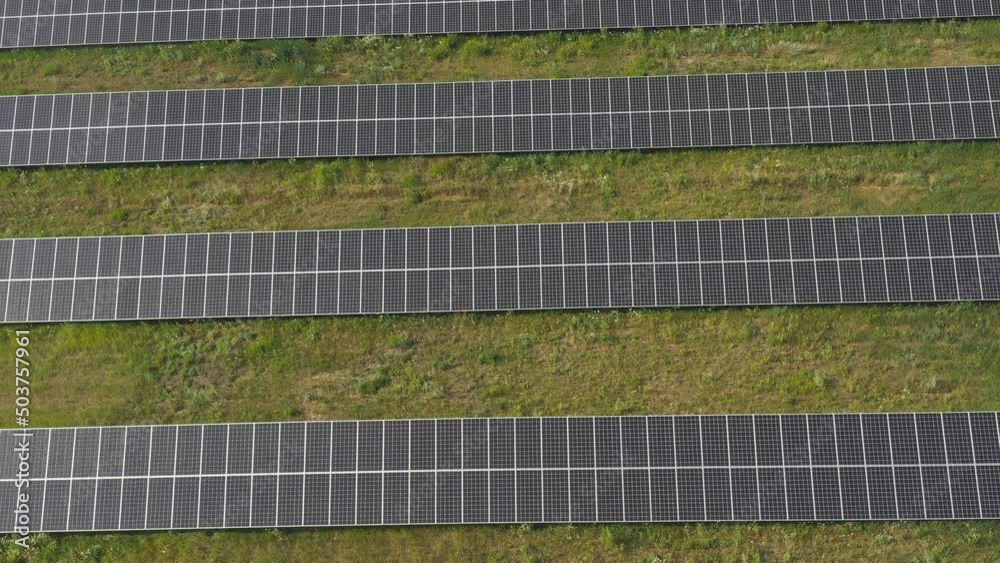 Aerial shot of rows of solar panels installed on meadow and generating electricity. Getting clean ecology friendly energy from the sun. Concept of modern renewable green energy. Top view Close up Aerial shot of rows of solar panels installed on meadow and generating electricity. Getting clean ecology friendly energy from the sun. Concept of modern renewable green energy. Top view Close up