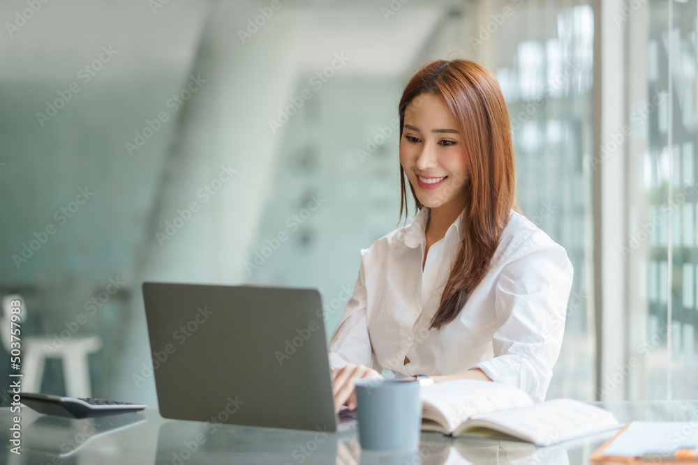 Portrait of young Asian business woman using laptop in the office. Portrait of young Asian business woman using laptop in the office.