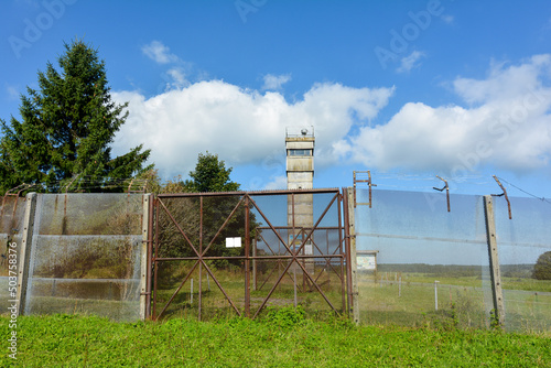 A watchtower on a former GDR border fortification with a barbed wire fence and a blue sky