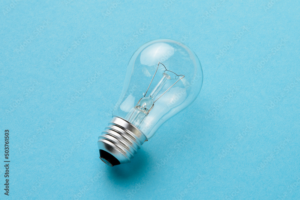 Incandescent lamp isolated on blue background closeup.