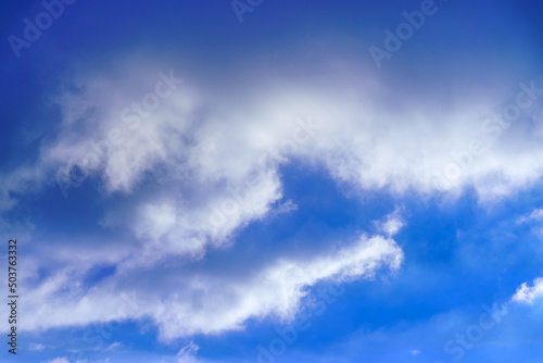 Summer sky. White clouds in the blue sky. Heaven and infinity. Beautiful bright blue background. Light cloudy, good weather. Curly clouds on a sunny day