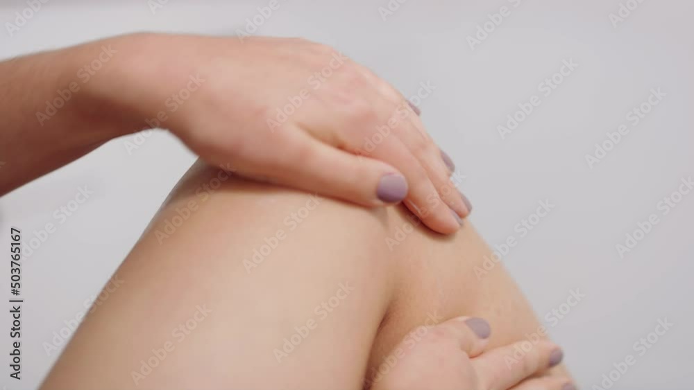 Woman rubs lotion around her knee in slow motion in white bathroom Woman rubs lotion around her knee in slow motion in white bathroom
