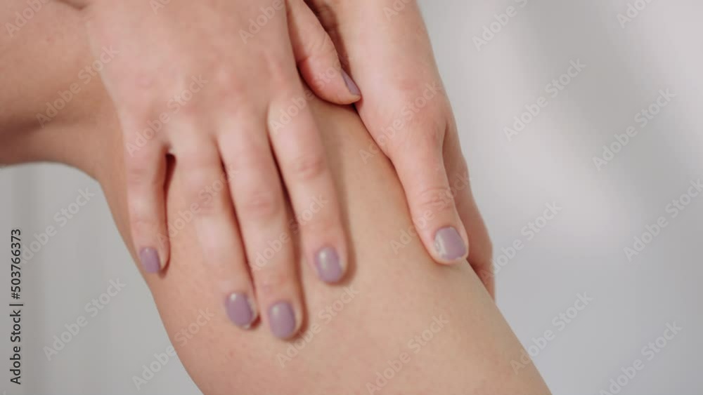 Woman luxuriously rubs moisturizer up and down legs, shin, and knee Woman luxuriously rubs moisturizer up and down legs, shin, and knee