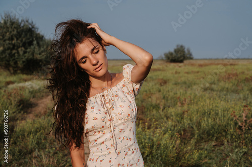 Close-up. Portrait of a young Caucasian woman enjoying nature on picturesque steppe landscape. Autumn or summer