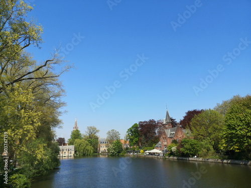 Blick von der Minnewaterbrücke  auf das Kasteel Minnewater und das Sashuis vor blauem Himmel im Sonnenschein in der Altstadt von Brügge in Westflandern in Belgien photo