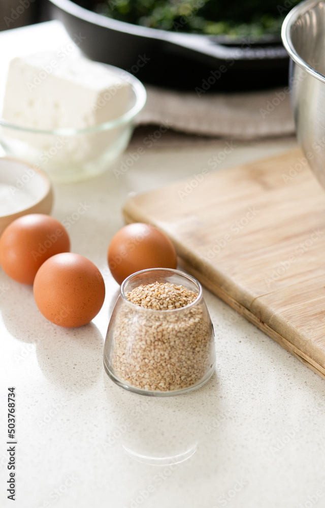 small bowl of sesame seeds with three eggs and other ingredients on kitchen counter small bowl of sesame seeds with three eggs and other ingredients on kitchen counter