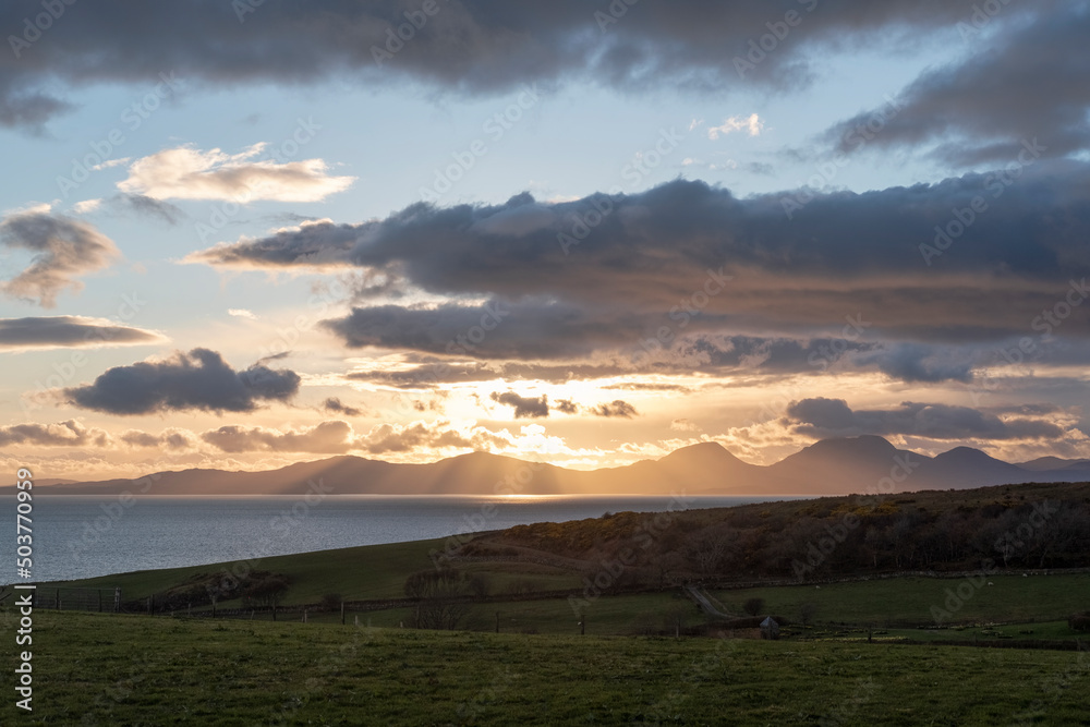 Fabulous sunset near Kilberry village in Argyll and Bute, with crepuscular rays piercing through the heavy dark clouds, beautiful twilight over one of the most remote parts of the Scottish Highlands
