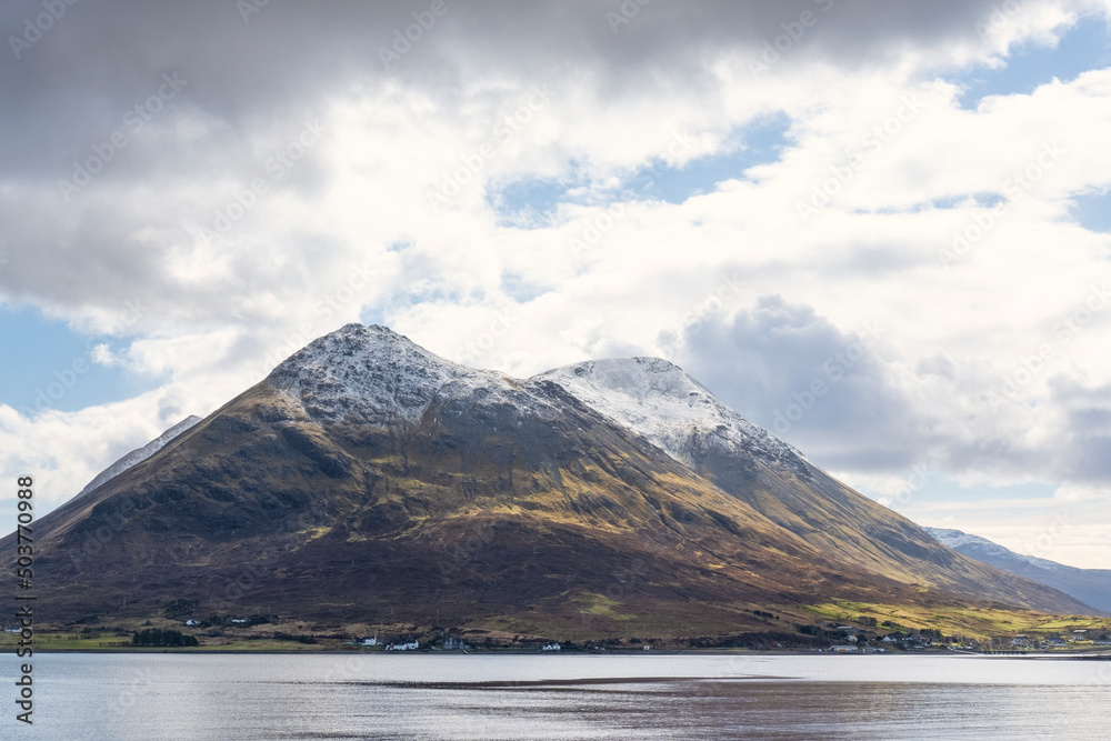 Views of the ethereal landscape, primordial nature and frozen atmosphere, of the Isle of Skye with the snow caps of Glamaig peak and the tranquil Loch Sigachan, as seen from Isle of Raasay, Scotland