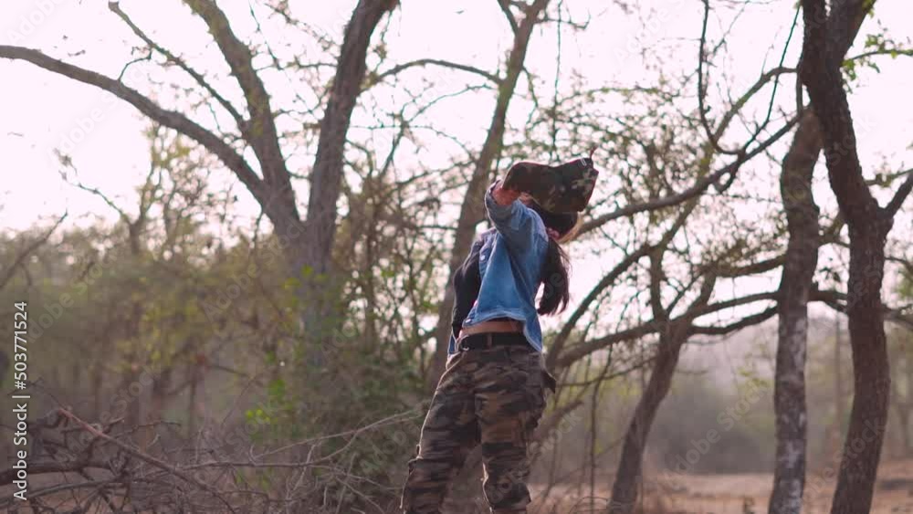 Portrait of happy Indian female holding camera in hand and spreading arms while standing at forest. Woman enjoying nature at Sasan Gir, Junagadh, India. Portrait of happy Indian female holding camera in hand and spreading arms while standing at forest. Woman enjoying nature at Sasan Gir, Junagadh, India.