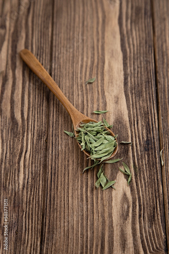 Dry thyme leaves pile in a wooden spoon on a wooden background,top view