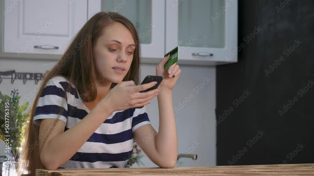 Girl is shopping online. Credit card in hand of girl. Smartphone e-commerce. Purchase online by credit card. Girl makes an online purchase. E-commerce concept. Smartphone and credit card in woman hand Girl is shopping online. Credit card in hand of girl. Smartphone e-commerce. Purchase online by credit card. Girl makes an online purchase. E-commerce concept. Smartphone and credit card in woman hand